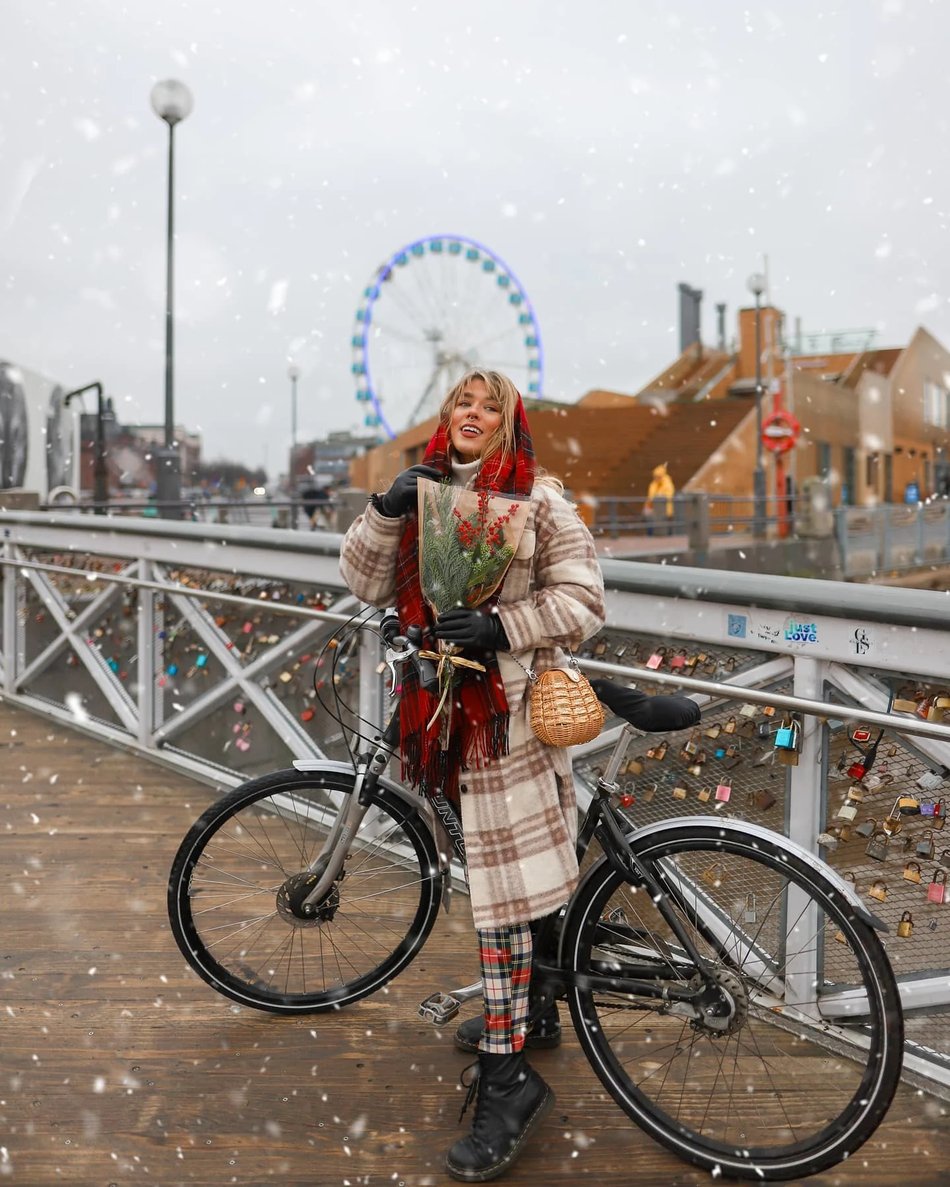 Female social media influencer holding flowers while posing in front of a bike by Allas Seapool in Helsinki. Authentic image from a campaign with the City of Helsinki. 