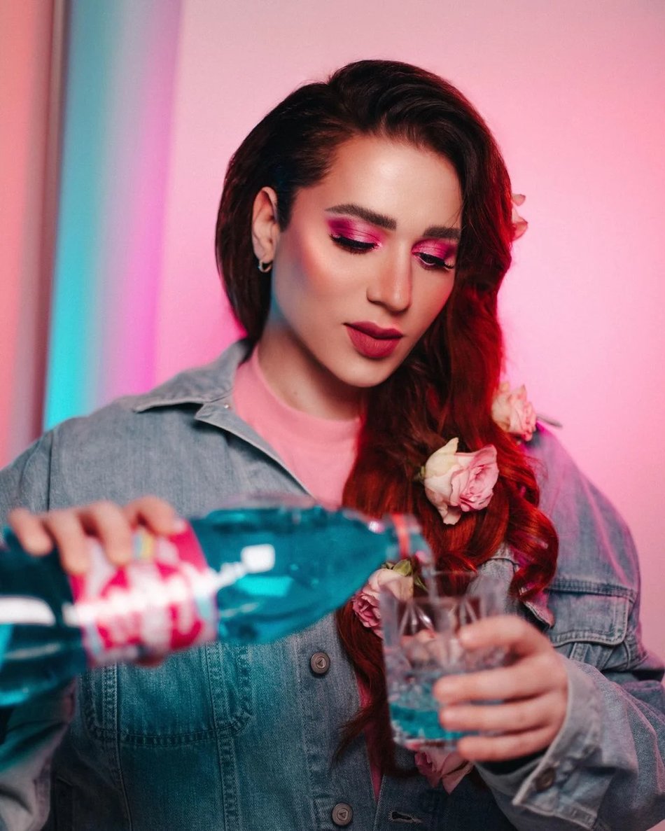 Social content with an Instagram influencer pouring a soft drink to a glass in a neon colored setting. 